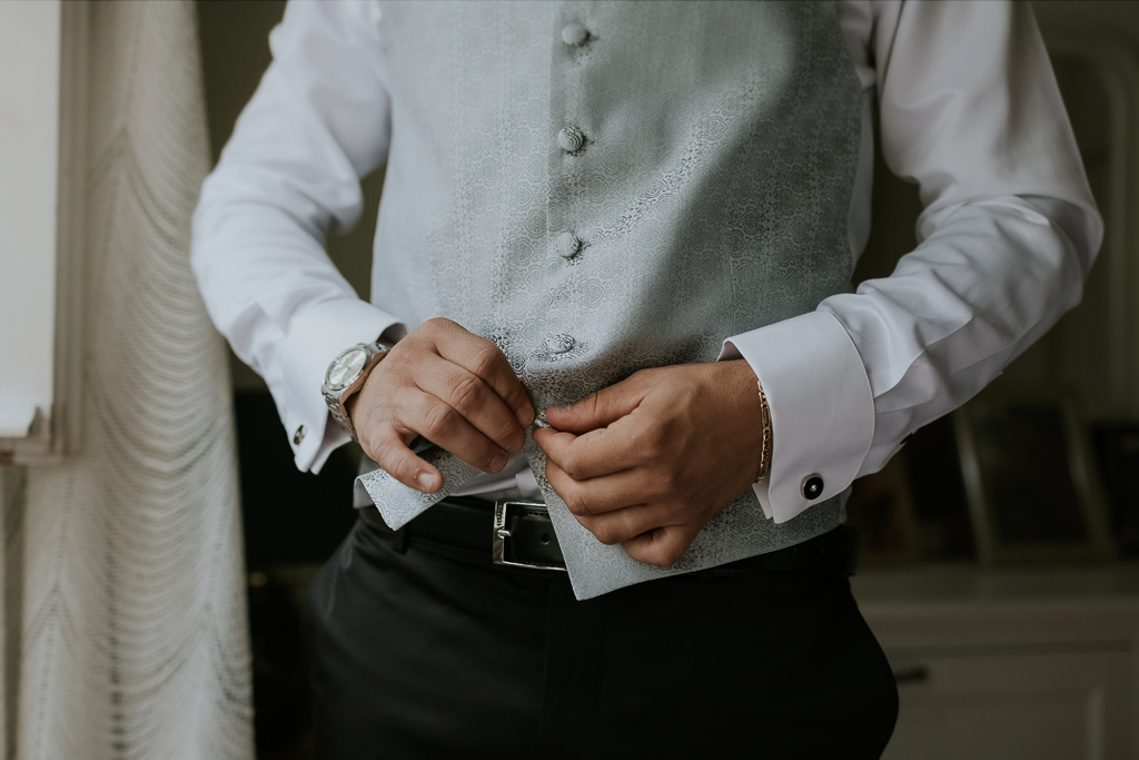 sposo abbottona il gilet per il matrimonio a roma