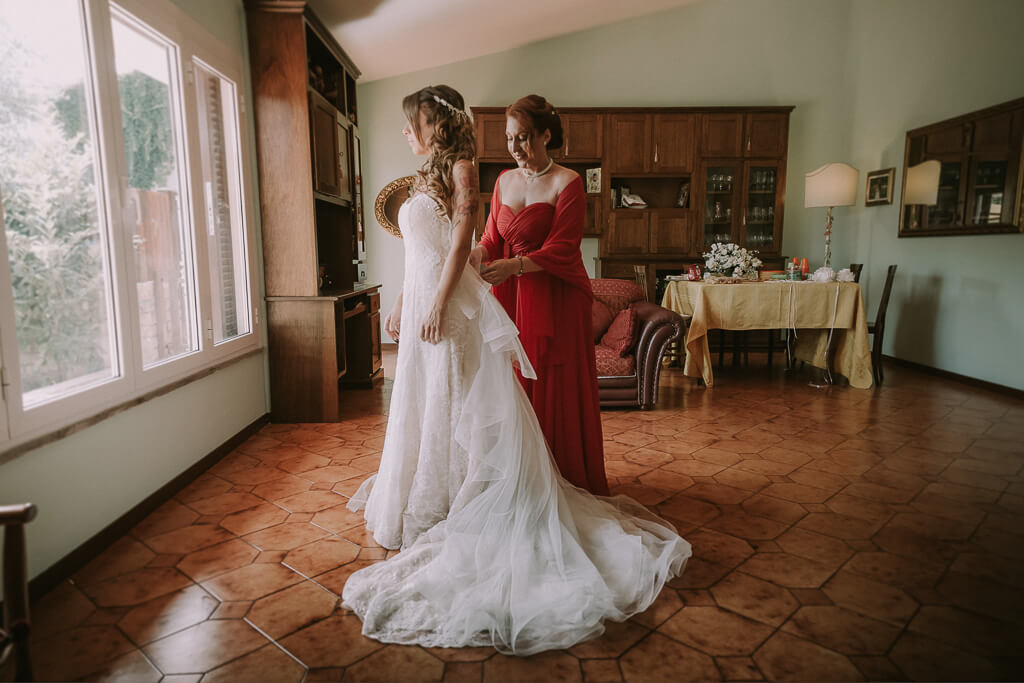 la mamma chiude il vestito della sposa