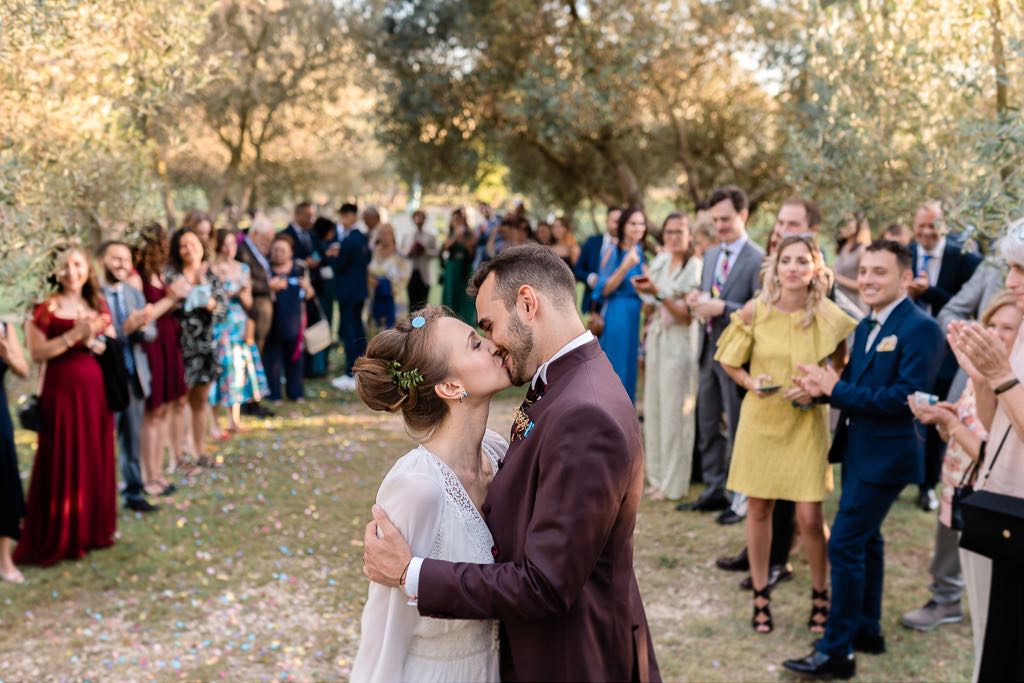 gli sposi si baciano dopo la cerimonia mentre gli ospiti attorno applaudono