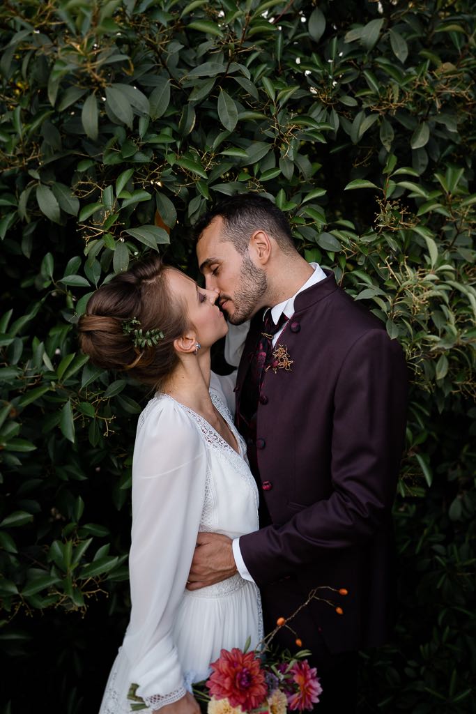 gli sposi si baciano davanti alla siepe