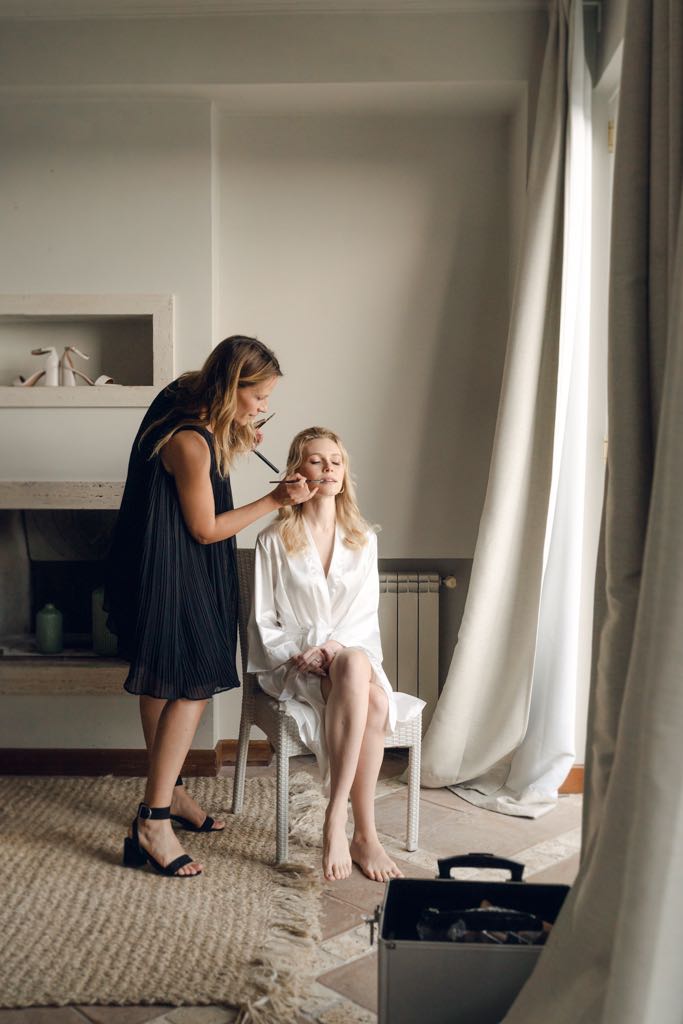 la sposa si trucca vicino alla finestra
